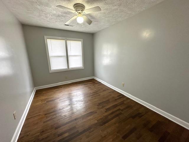 empty room featuring ceiling fan, dark hardwood / wood-style floors, and a textured ceiling