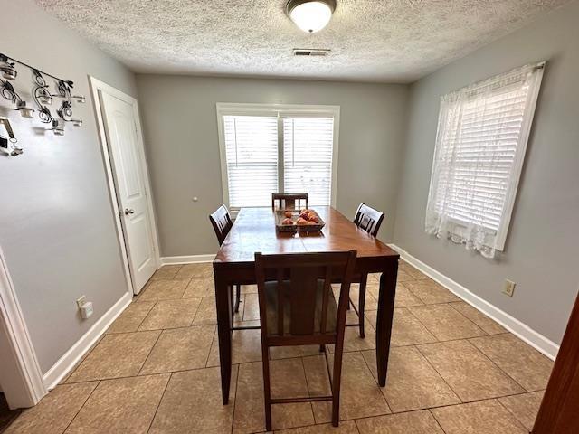 tiled dining space featuring a textured ceiling