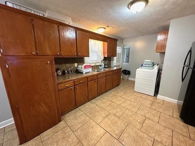 kitchen with black refrigerator, washer / clothes dryer, sink, and a textured ceiling