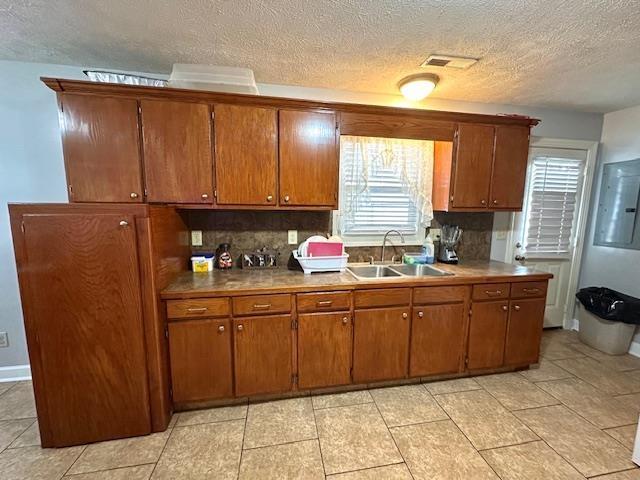 kitchen featuring tasteful backsplash, sink, light tile patterned floors, and a textured ceiling