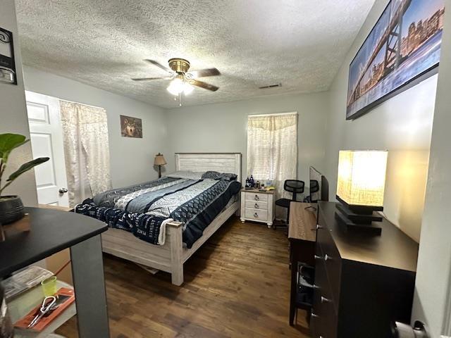 bedroom with ceiling fan, dark hardwood / wood-style floors, and a textured ceiling