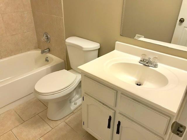 full bathroom with vanity, tiled shower / bath, tile patterned floors, and toilet