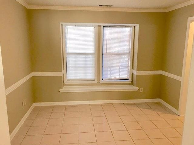 tiled spare room featuring crown molding