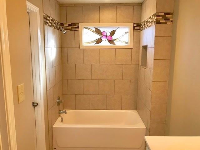 bathroom featuring tiled shower / bath combo and vanity