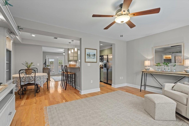 living room with french doors, ceiling fan, and light wood-type flooring