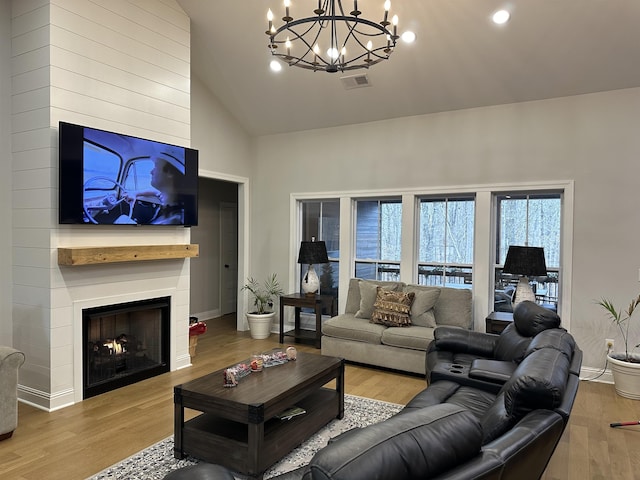 living room with high vaulted ceiling, a fireplace, and light hardwood / wood-style floors