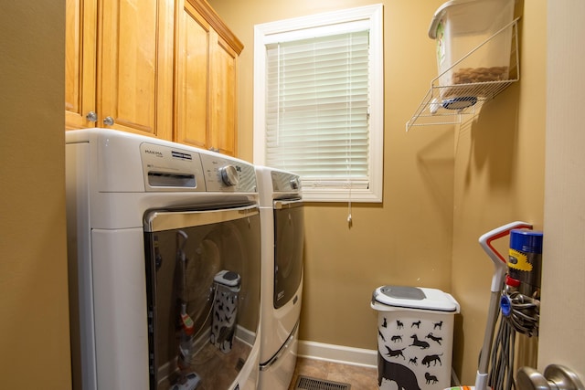 clothes washing area featuring separate washer and dryer, tile patterned flooring, and cabinets