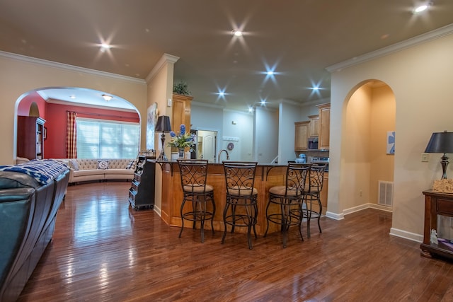 kitchen featuring a kitchen breakfast bar, crown molding, dark hardwood / wood-style floors, and light brown cabinetry