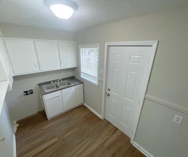 laundry area with wood-type flooring, sink, and a textured ceiling