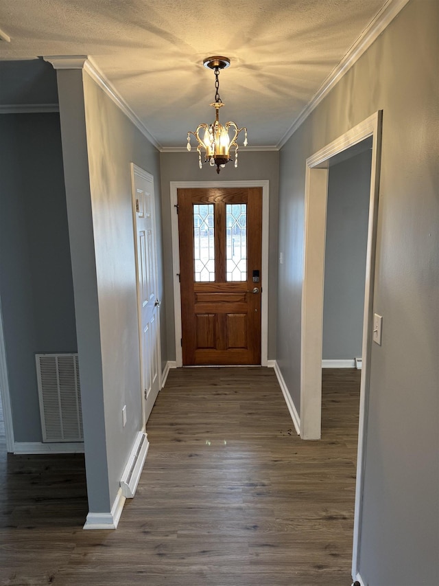 foyer entrance with crown molding, dark wood-type flooring, a textured ceiling, and a chandelier