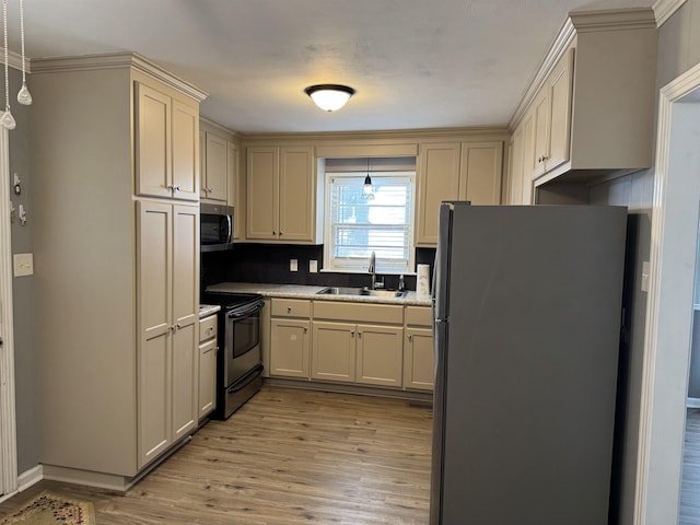 kitchen with pendant lighting, sink, light hardwood / wood-style flooring, stainless steel appliances, and cream cabinetry