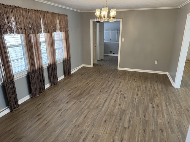 spare room featuring crown molding, a wealth of natural light, dark wood-type flooring, and a notable chandelier