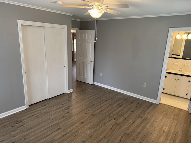 unfurnished bedroom featuring sink, connected bathroom, ornamental molding, dark hardwood / wood-style flooring, and a closet