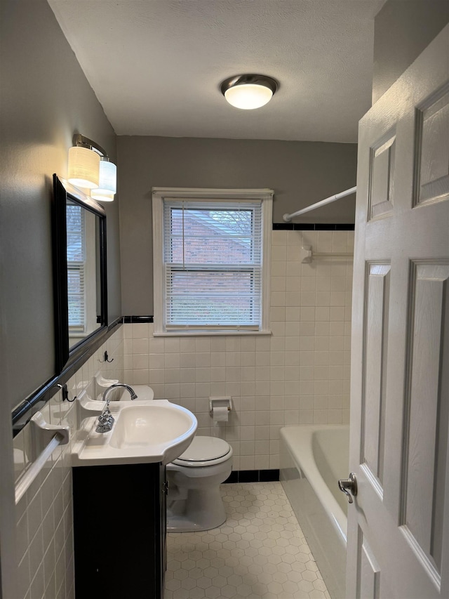 full bathroom with toilet, tile walls, a textured ceiling, vanity, and tile patterned flooring