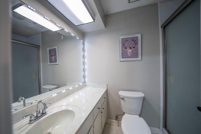 bathroom with baseboards, toilet, vanity, and a shower stall