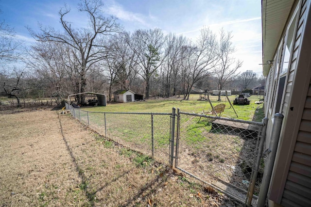 view of yard with driveway, an outbuilding, a gate, fence, and a carport