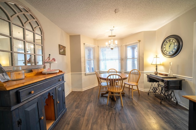 dining area featuring dark wood-style flooring, visible vents, a notable chandelier, and a textured ceiling
