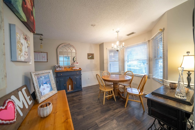 dining space featuring a textured ceiling, dark wood-style flooring, visible vents, and a notable chandelier