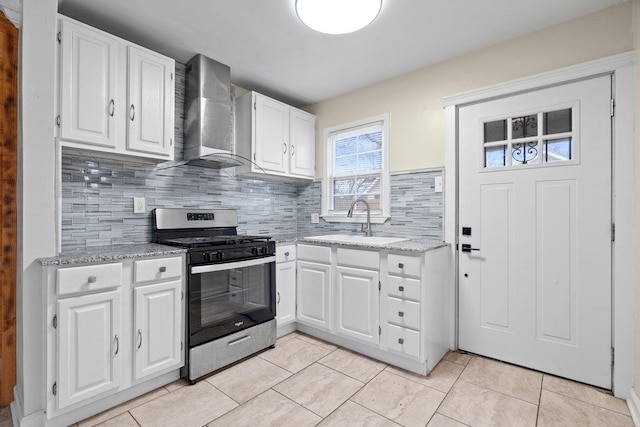 kitchen featuring wall chimney exhaust hood, stainless steel range with gas stovetop, and white cabinets