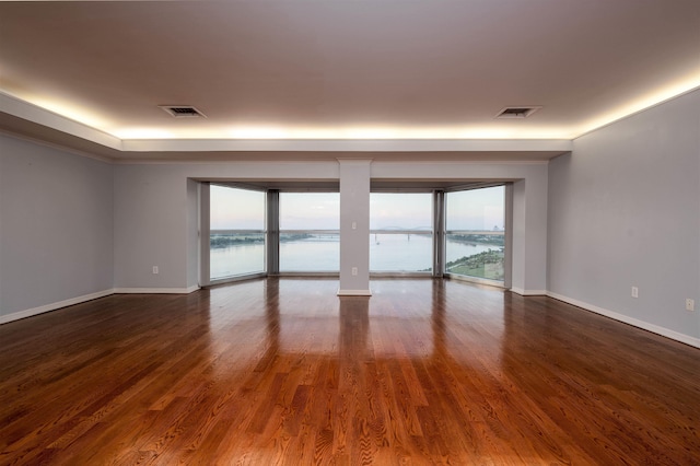 unfurnished room featuring a water view and dark hardwood / wood-style floors