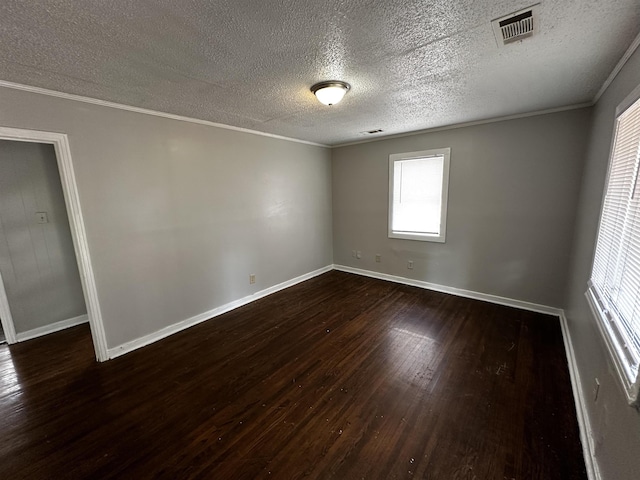 spare room featuring ornamental molding, dark wood-type flooring, and a textured ceiling