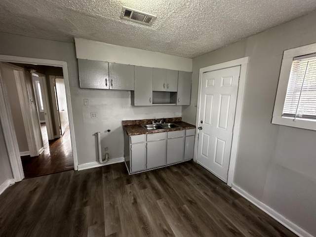 kitchen featuring dark wood-type flooring, gray cabinets, sink, and a textured ceiling