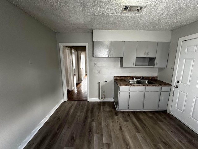 kitchen featuring gray cabinets, sink, dark wood-type flooring, and a textured ceiling