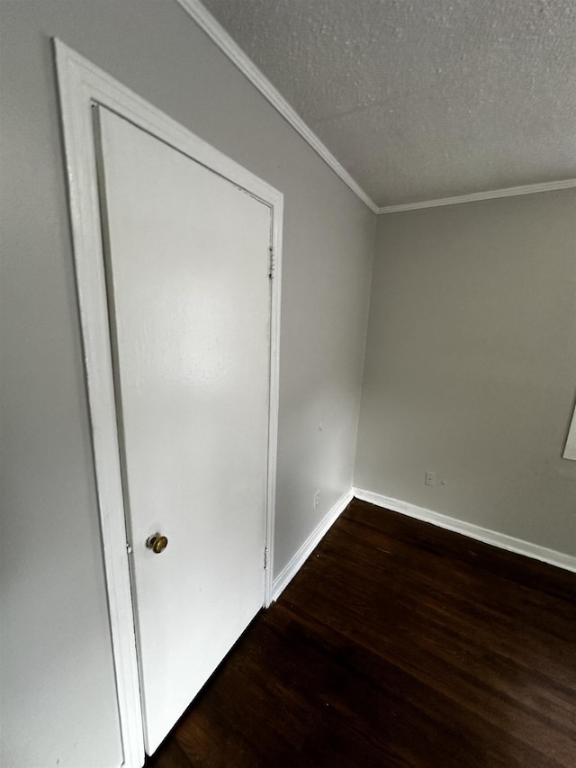 spare room with dark wood-type flooring, crown molding, and a textured ceiling