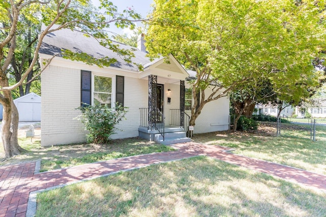 view of front of home with a shed and a front lawn