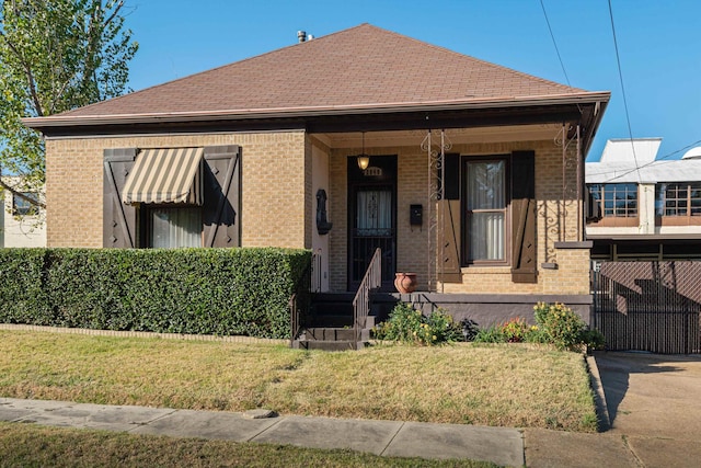 bungalow-style home featuring covered porch and a front yard