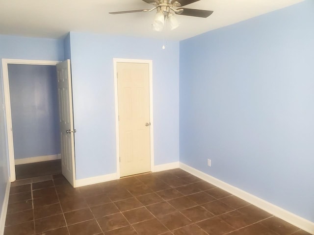 unfurnished bedroom with dark tile patterned floors and ceiling fan