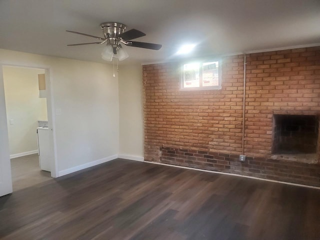 spare room featuring dark hardwood / wood-style flooring, ceiling fan, and brick wall