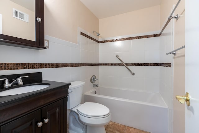 full bathroom featuring vanity, toilet, tiled shower / bath combo, and tile walls