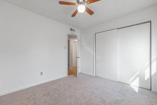 unfurnished bedroom with ceiling fan, a closet, and light carpet