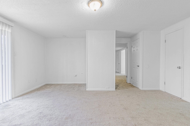 spare room with light colored carpet and a textured ceiling