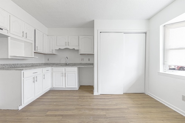 kitchen featuring a textured ceiling, light hardwood / wood-style flooring, and white cabinets