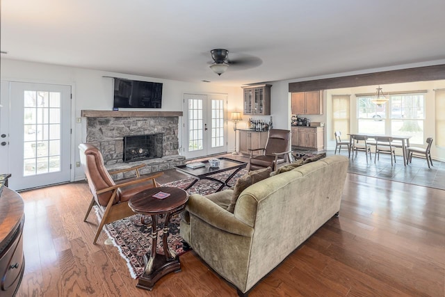 living room with french doors, ceiling fan, wood-type flooring, and a fireplace