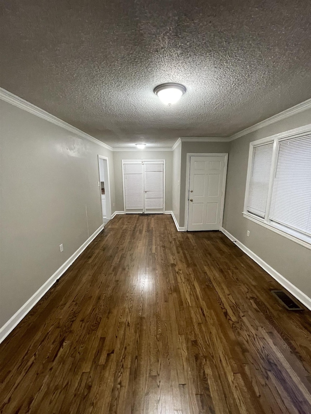 interior space with dark wood-type flooring, ornamental molding, and a textured ceiling