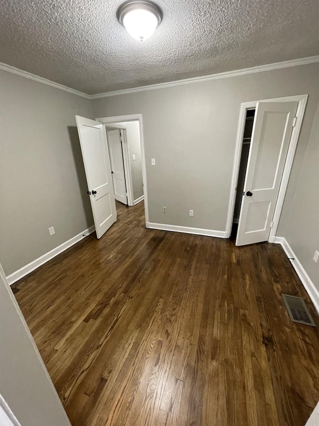 unfurnished bedroom with dark wood-type flooring, ornamental molding, and a textured ceiling