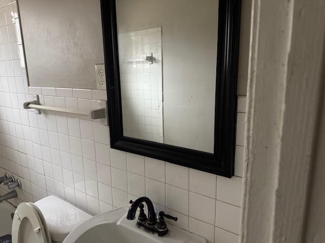 bathroom with sink, tile walls, and toilet