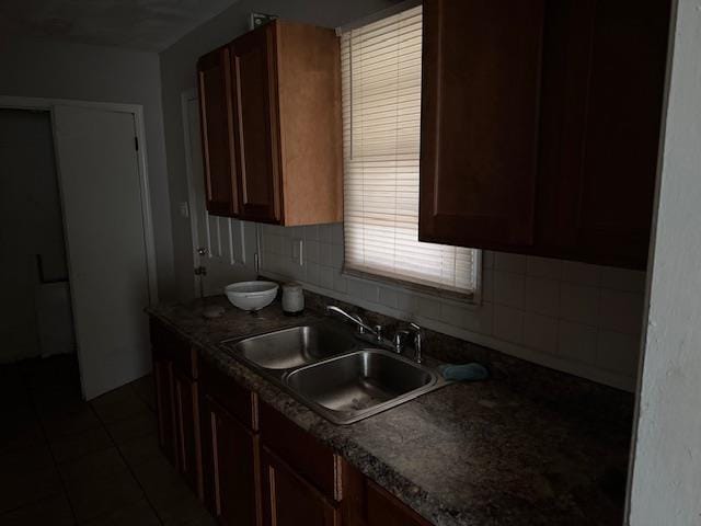 kitchen with dark tile patterned flooring, sink, and decorative backsplash