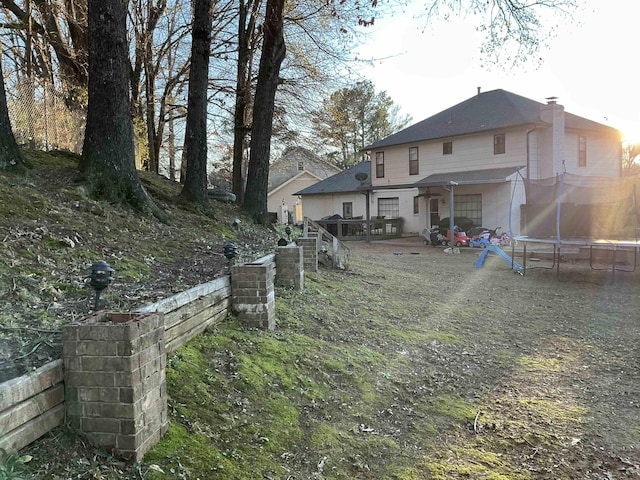 rear view of property with a trampoline and a patio area