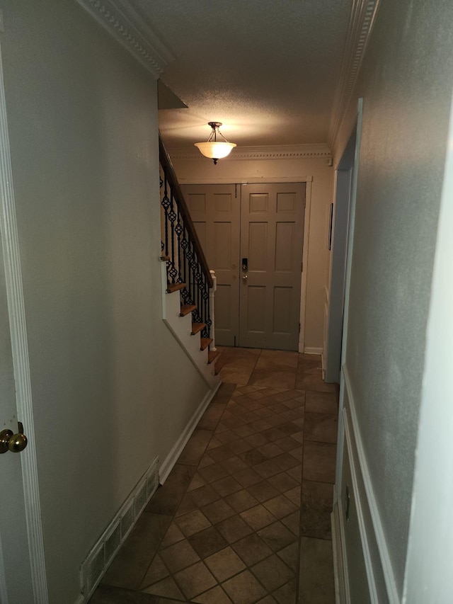 entryway with crown molding and a textured ceiling