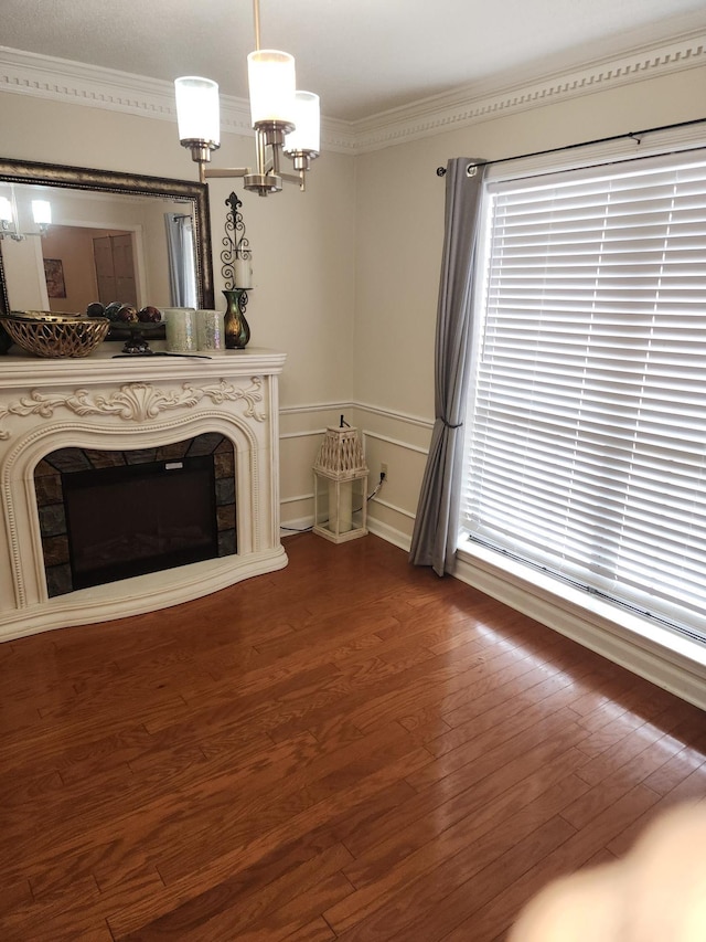 unfurnished living room featuring an inviting chandelier, ornamental molding, a fireplace, and hardwood / wood-style floors