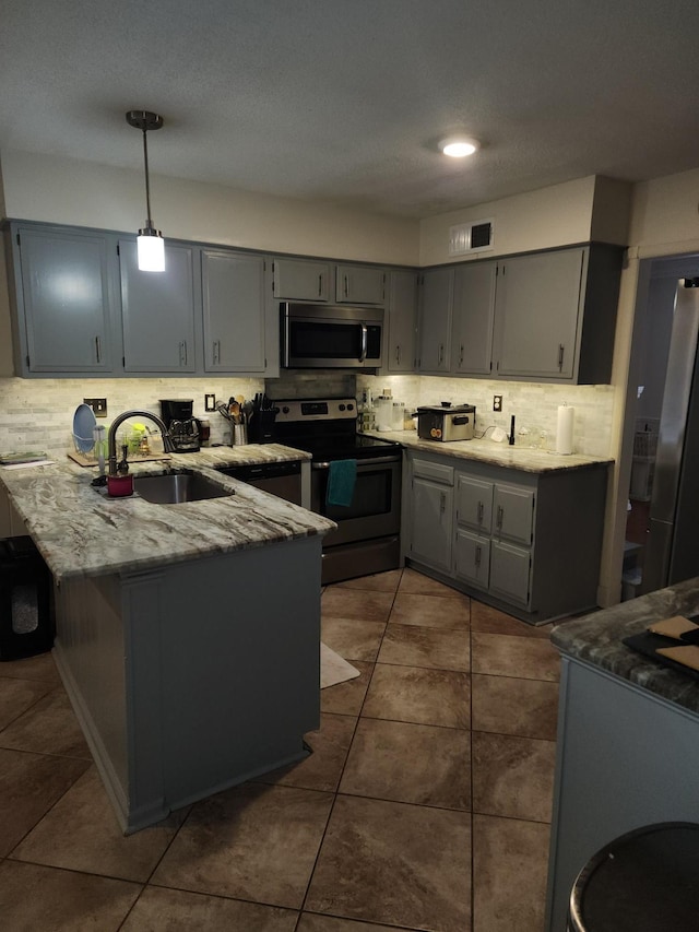 kitchen featuring sink, hanging light fixtures, appliances with stainless steel finishes, gray cabinets, and kitchen peninsula