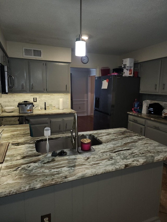 kitchen with gray cabinetry, sink, decorative light fixtures, and black refrigerator with ice dispenser