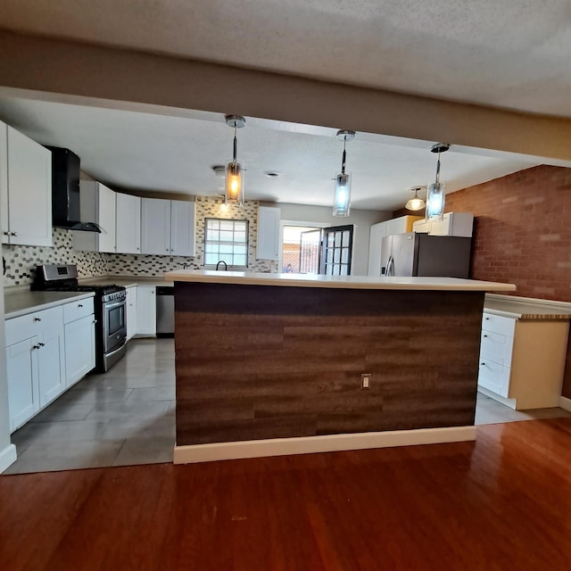 kitchen with white cabinetry, hanging light fixtures, wall chimney exhaust hood, and appliances with stainless steel finishes