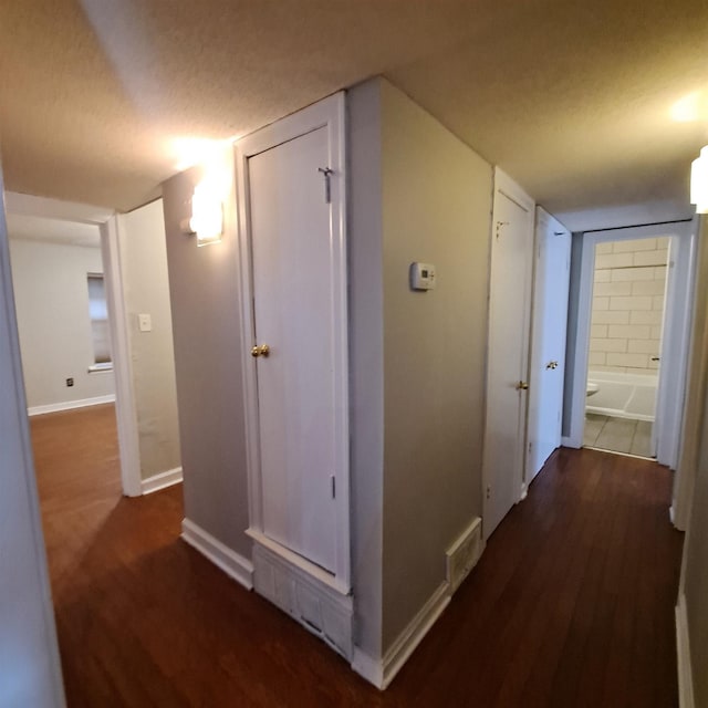 hall with dark hardwood / wood-style floors and a textured ceiling