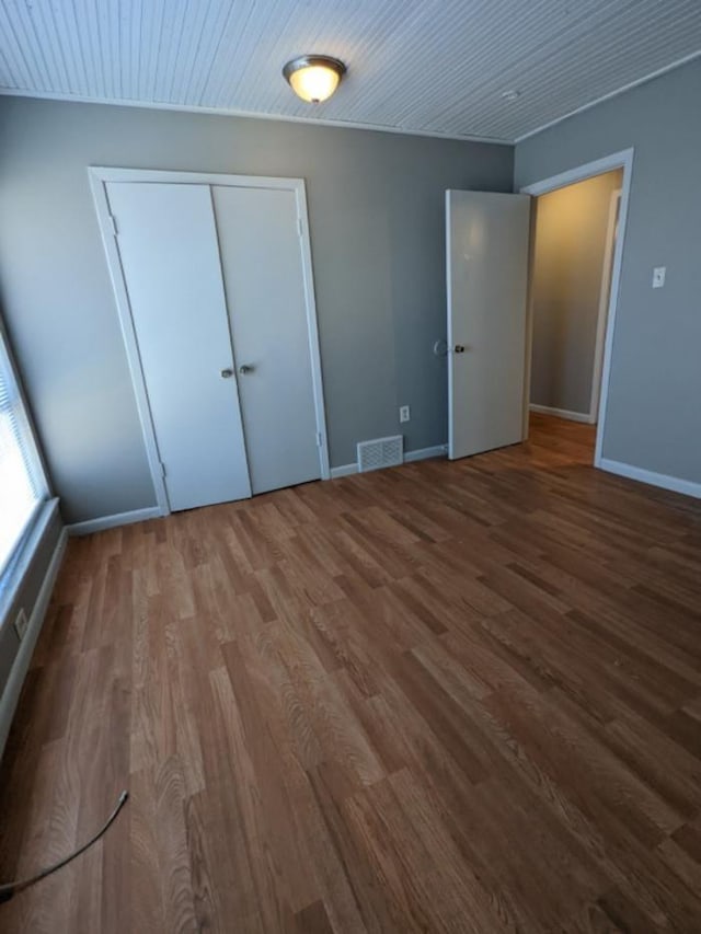 unfurnished bedroom featuring wood ceiling, wood-type flooring, and a closet