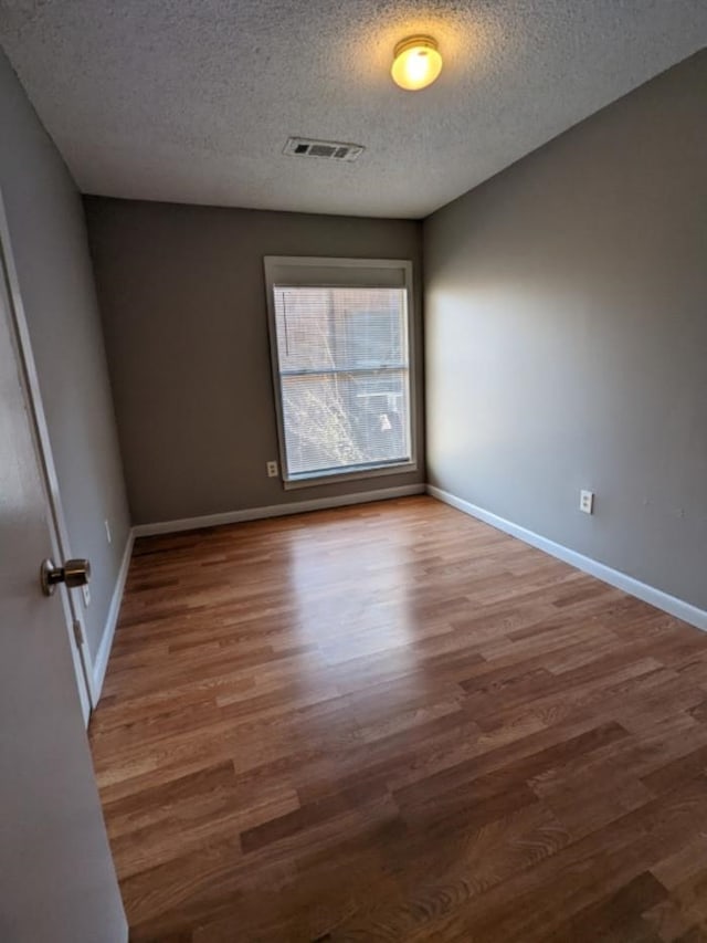 spare room featuring hardwood / wood-style flooring and a textured ceiling